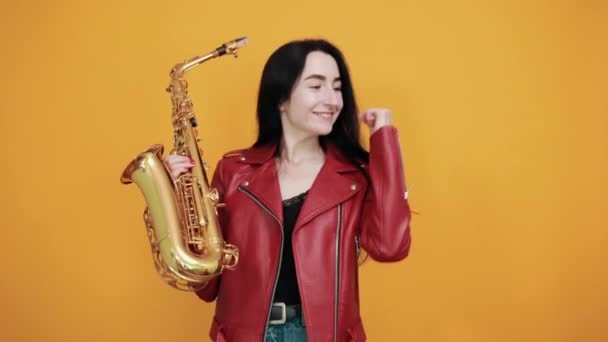 Mladá brunetka drží saxofon, dělá vítězný gesto říct ano. — Stock video