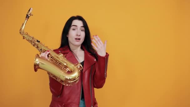 Calma jovem senhora mantendo a boca fechada e saxofone, colocando as mãos sobre as bochechas — Vídeo de Stock