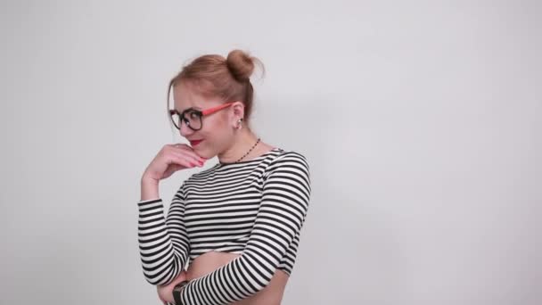 Молода жінка з сумнівами, дивлячись прямо на ізольовану білу стіну — стокове відео