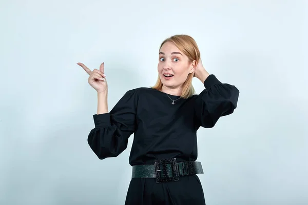 Ung kvinna i casual kläder pekar pekfinger åt sidan, sätta hand på huvud — Stockfoto
