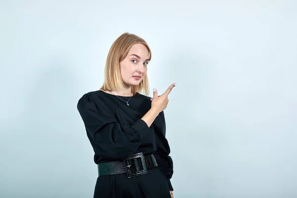 Attraente giovane donna rasata in giacca nera che mostra sullo spazio di lavoro su blu — Foto Stock