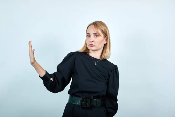 Serious young woman in dark clothes showing stop gesture with palm aside — Stock Photo, Image