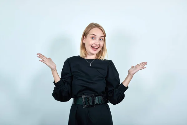 Smiling young woman in black clothes spreading hands, looking camera — Stock Photo, Image