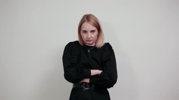 Strenge junge Frau, Schal, die Hände vereinzelt an weißer Wand verschränkt — Stockvideo