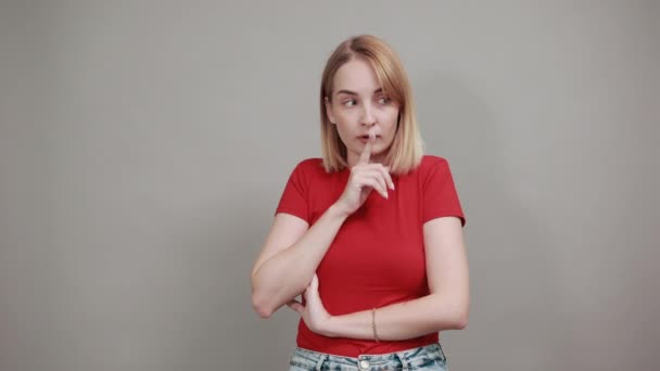 Hübsche junge Frau sagt Schweigen sei still mit dem Finger auf den Lippen shhh Geste — Stockvideo