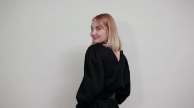 Gülen genç kadın beyaz duvarda tek başına geriye bakıyor.