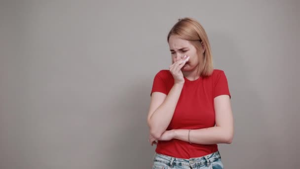 Retrato de uma jovem confusa olhando para o lado e cobrindo o nariz com a mão — Vídeo de Stock