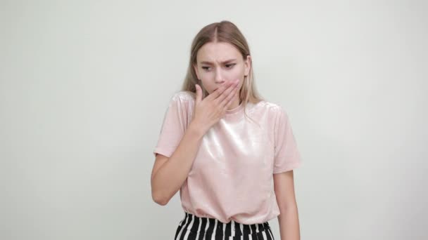 Ung blond kvinna med överraskande ansiktsuttryck, täcker munnen med handen — Stockvideo