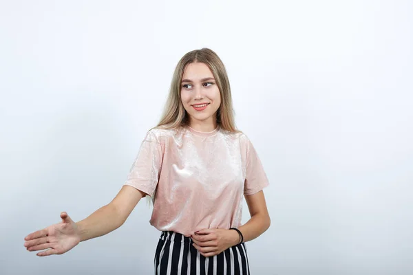 Ελκυστική νεαρή γυναίκα στέκεται με απλωμένο χέρι για χαιρετισμό — Φωτογραφία Αρχείου