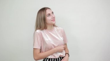 İzole edilmiş beyaz duvarın üzerinden elini kaldıran beyaz bir kadın.