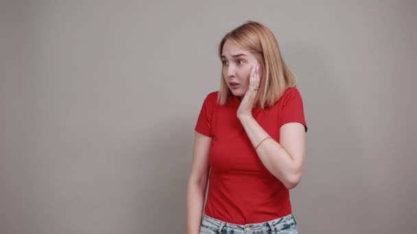 Mooie jonge vrouw in rood shirt poseren, sceptisch geschokt uitzicht — Stockvideo
