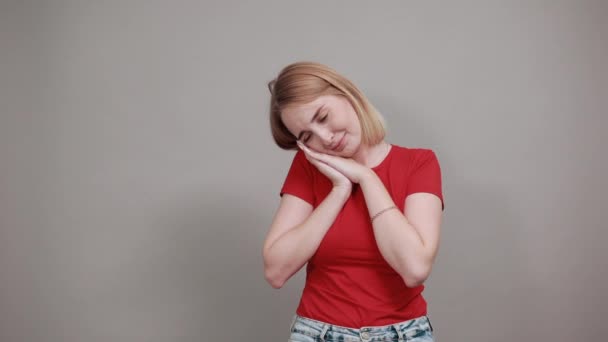 Mujer joven excitada en camisa roja manteniendo las manos cerca de la cara aislada en gris — Vídeos de Stock