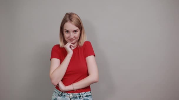 Pensive young woman in red shirt looking aside, put hand prop up on chin — Stock Video