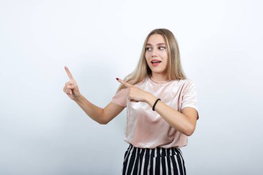 Neşeli kadın portresi beyaz duvarda izole edilmiş kazanan gibi parmaklarını kaldırıyor.