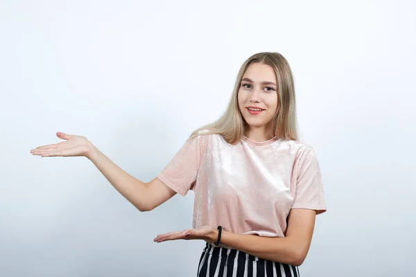 Porträtt av en ung kvinna som håller något, tittar direkt och pekar med händerna — Stockfoto