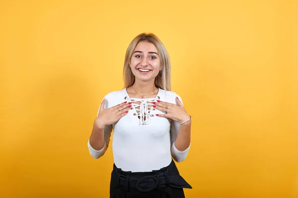 Porträtt av leende trevlig ung kvinna i vit skjorta hålla händerna på bröstet. — Stockfoto