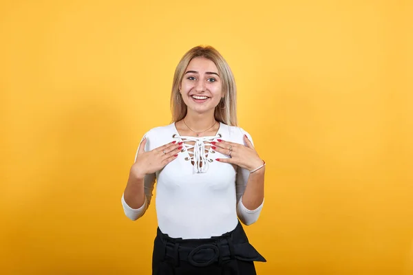 Portrait de jeune femme agréable et souriante en chemise blanche tenant la main sur la poitrine . — Photo