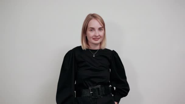 Smiling young woman spreading hands, looking camera isolated on white wall — Stock Video