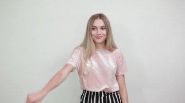 İzole edilmiş beyaz bir duvarda, moda kıyafetleri içinde parmak izi bırakan bir kız.