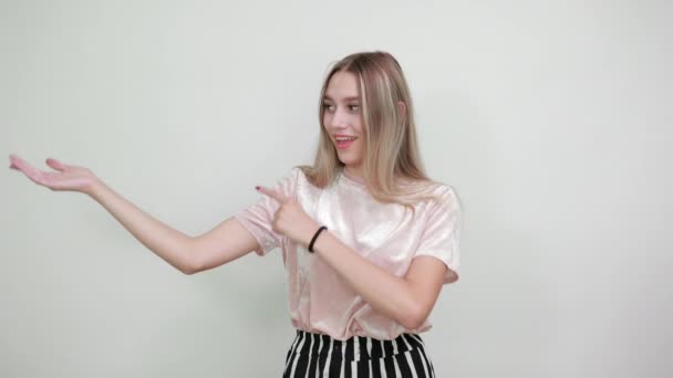 Arckép fiatal nő szép ruhák emelkedő ujjak félre, mutatja a helyet — Stock videók