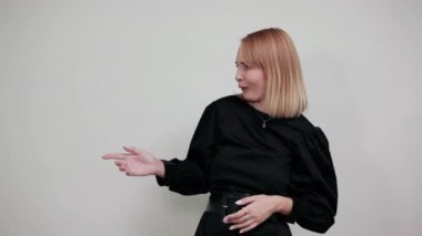 Gündelik giysiler içinde genç bir kadın bir şey tutuyor, bir tarafa bakıyor ve işaret ediyor.