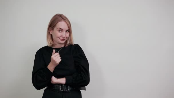 Vidám fiatal nő mutató mutatóujj, kezét félre elszigetelt fehér fal — Stock videók