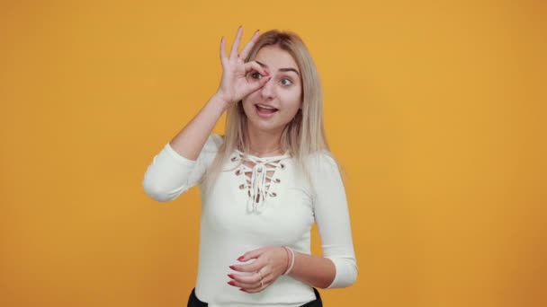 Young beautiful caucasian woman showing ok sign gesture near eyes like glasses — ストック動画