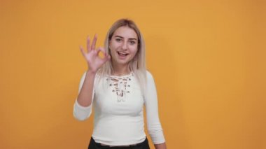 Genç, güzel, beyaz bir kadın. Gözlerinin yanında işaret işareti gösteriyor.