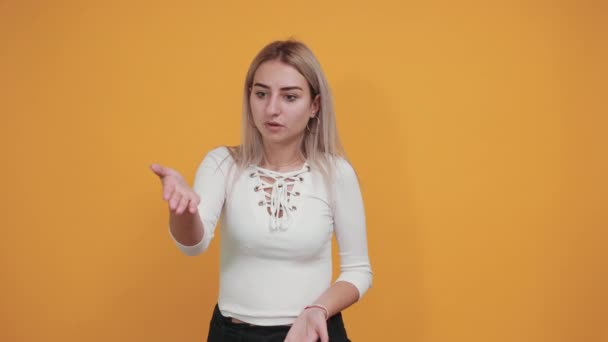 Ударна весела молода жінка в білій сорочці, дивиться камеру, розтягуючи руки — стокове відео