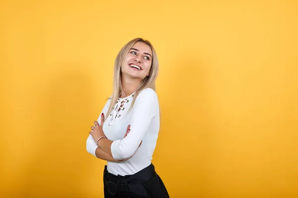 Femme souriante en vêtements décontractés tenant les mains croisées, isolée sur un mur orange — Photo