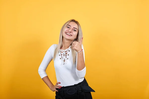 Ung kaukasisk dam glad och pekar knytnäve upp, hålla andra handen mot höften — Stockfoto