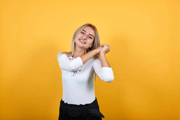 Sonriente mujer joven segura de sí misma en ropa blanca posando manteniendo las manos arriba —  Fotos de Stock