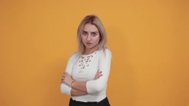 Şok olmuş beyaz gömlekli genç bir kadın, kameraya bakıyor, elini açıyor.