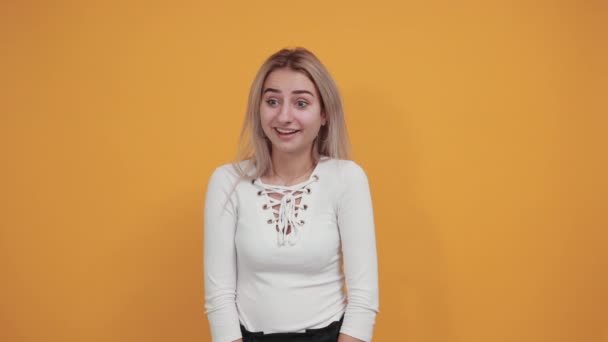 年轻迷人的女人用孤立的橙色背景捂住嘴 — 图库视频影像