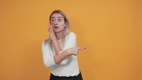 Jovem mulher caucasiana atraente gritando algo, mantendo a mão de lado — Vídeo de Stock