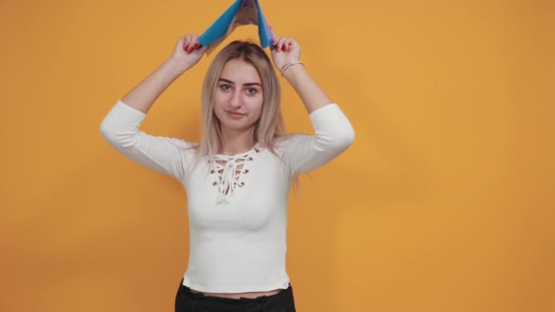 Νεαρή γυναίκα κορίτσι σε casual ρούχα θέτουν απομονωμένη σε πορτοκαλί τοίχο κρατήσει το φάκελο — Αρχείο Βίντεο