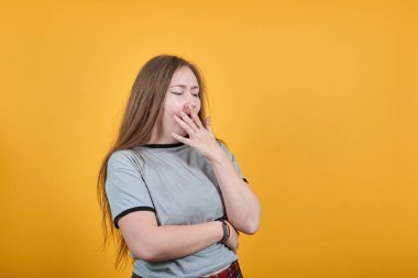 Güzel kız korkmuş ve şok olmuş görünüyor, elleri esneyerek ağzını kapatıyor.