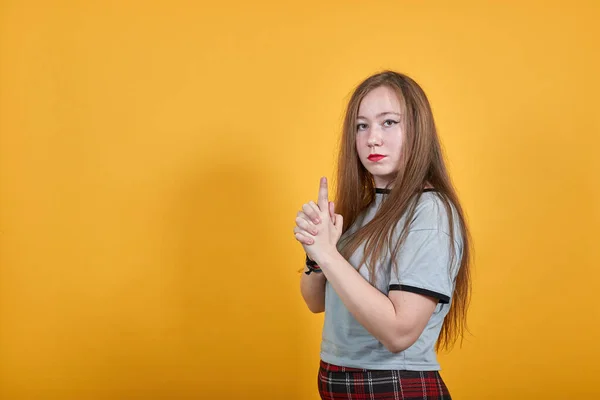 Retrato de mujer en camisa gris esperando con el dedo en alto como arma —  Fotos de Stock