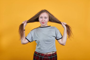 Gri elbiseli kadın kameraya bakıyor, saçı var, doğrudan bakıyor.