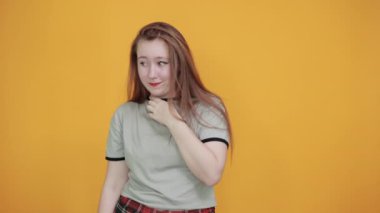 Genç, çekici esmer kadın. Gri elbiseler giyiyor. Ağzı eliyle kapatıyor.