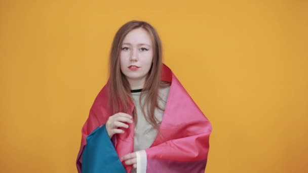 Frau blickt direkt, hält die Hände gekreuzt, betet, hält bisexuelle Fahne — Stockvideo