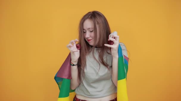 Caucásico dama mantener puños en el pecho, cubierto LGBT bandera se ve feliz, divertido — Vídeos de Stock