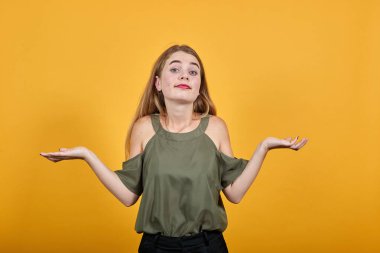 Beyaz tenli çekici kız omuzlarını kaldırırken önemsiz bir jest yapıyor.