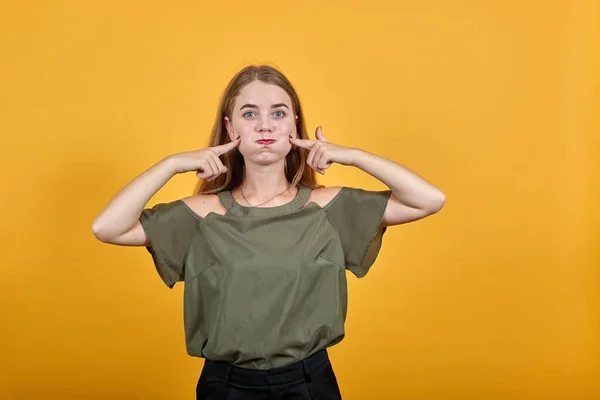 Jonge grappige dame draagt mooie blouse puffing wangen en houden vingers — Stockfoto