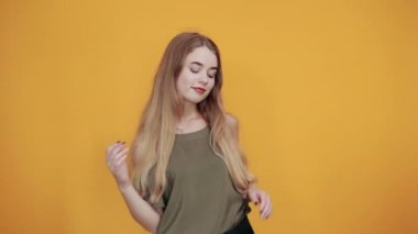 Çekici bir kadın gülümsüyor, çok komik görünüyor, ellerini yanaklarından ayırmıyor, gözleri kapalı.