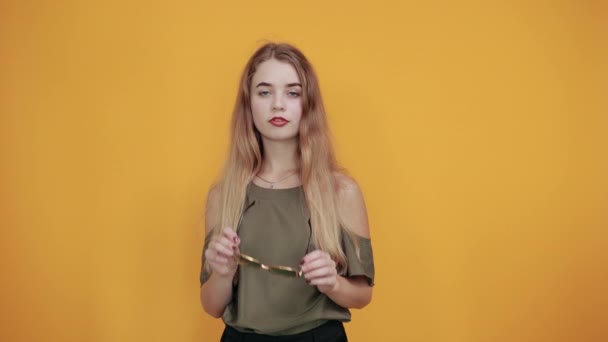 Opgewonden jong meisje in pastel kleding houden zonnebril houden handen op haar — Stockvideo