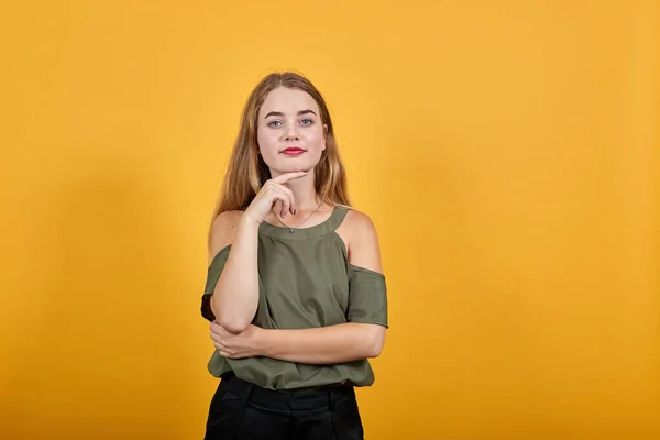 Genç ve güzel bir kadın doğrudan bakıyor, gözleri açık ve çenesinde bir el var.