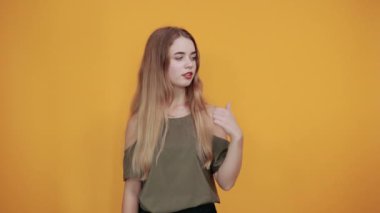 Yan tarafı gösteren bir kadın, baş parmağını bir kenara koyuyor, bir ürünü sunmak için gülümsüyor.