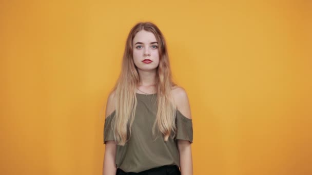 Fiatal vonzó nő, amely a száját a kezét az elszigetelt narancssárga fal — Stock videók