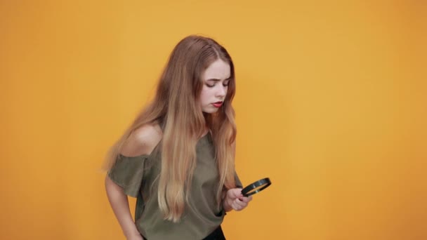 Jonge vrouw in mode shirt met een vergrootglas, op zoek serieus — Stockvideo